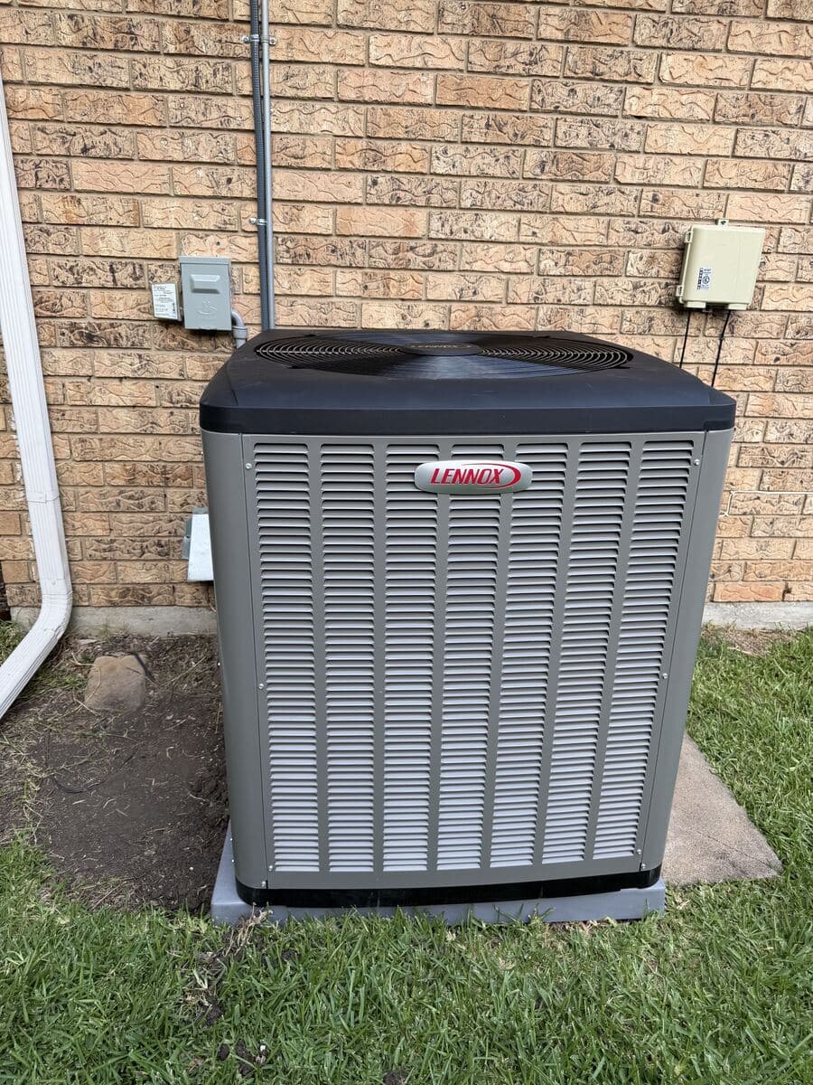Newly installed Lennox outdoor condensing unit on a level pad beside a Dallas brick home