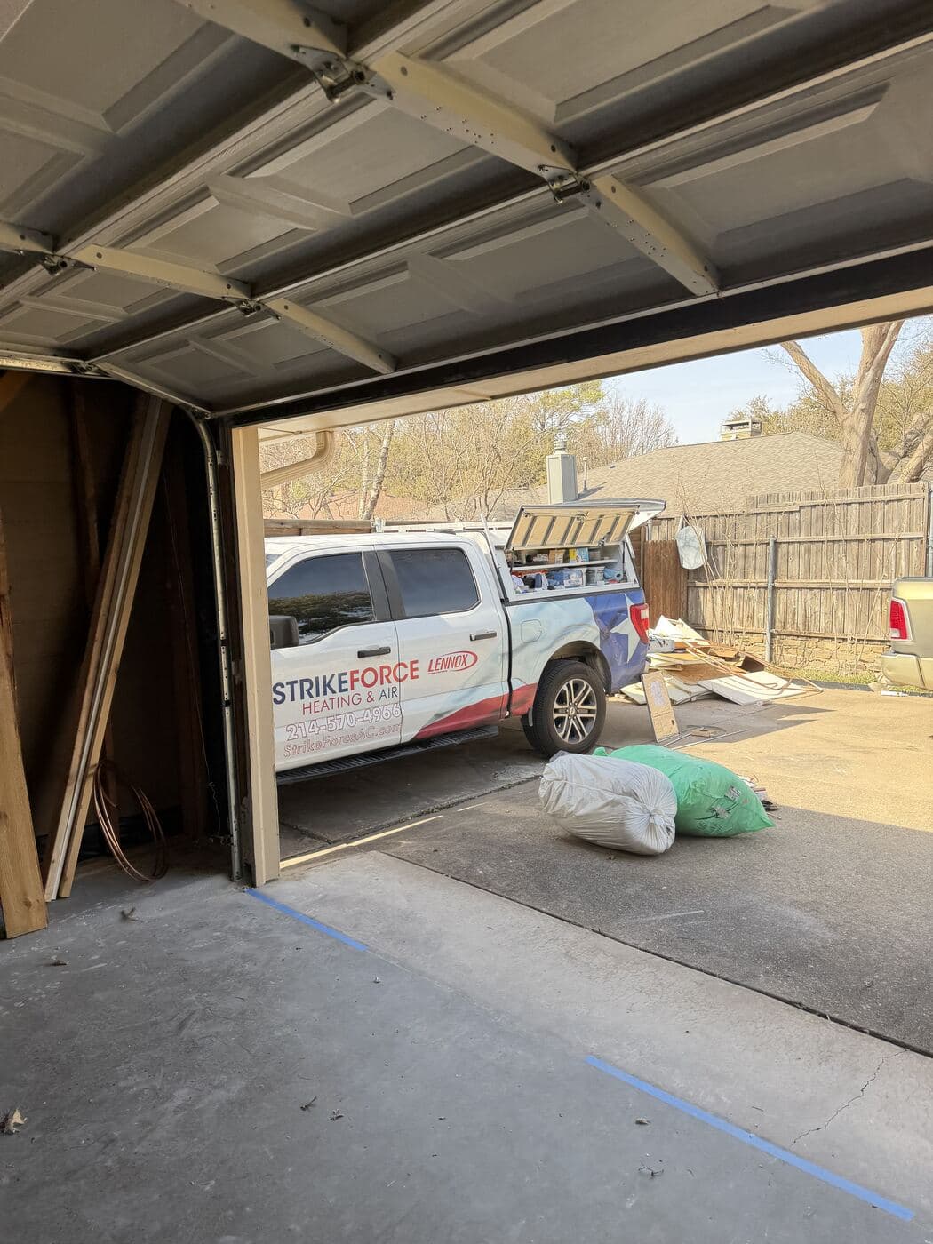 Strike Force service truck backed up to a customer's open garage during a system replacement