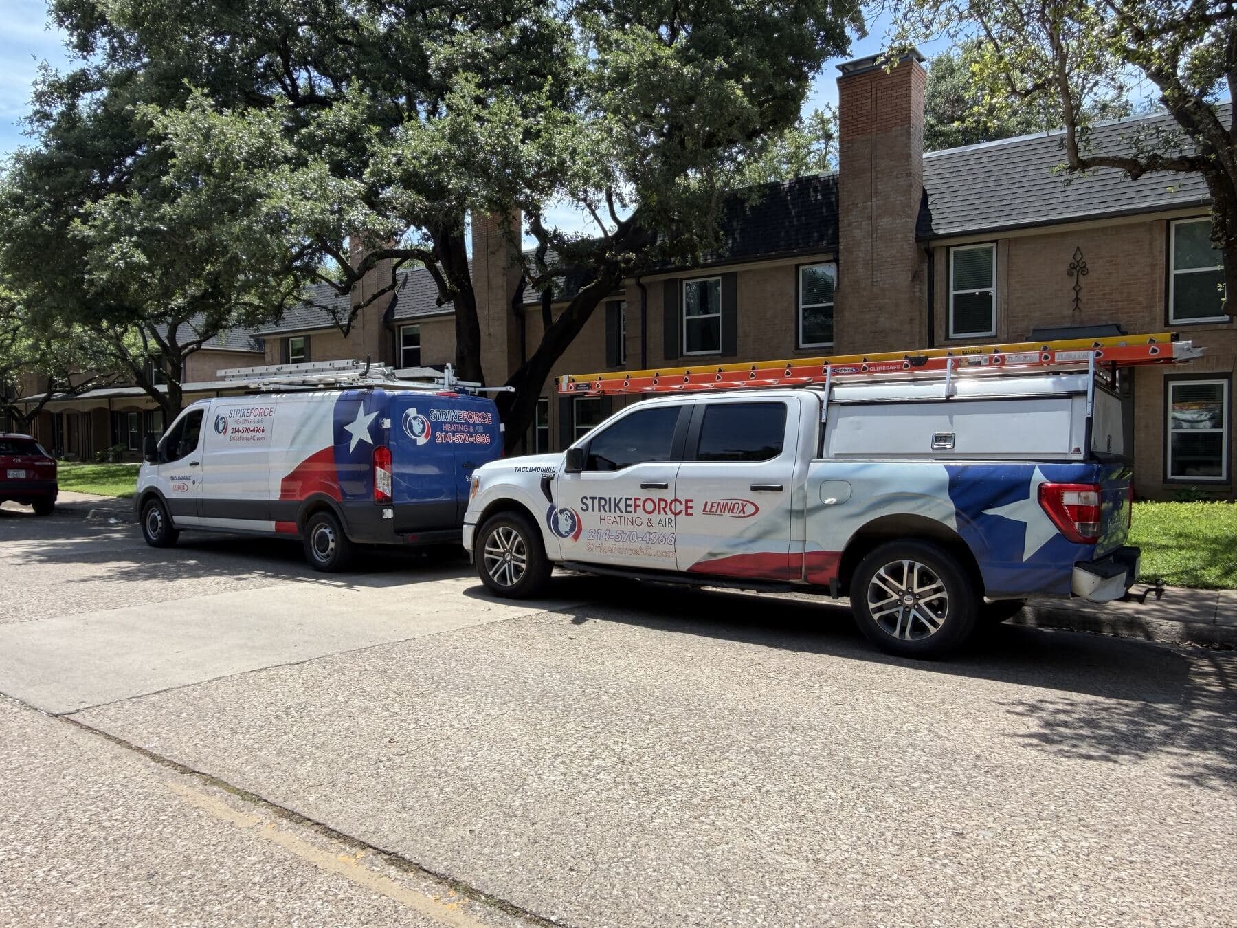 Two Strike Force Heating & Air trucks parked outside a Dallas home on an install day